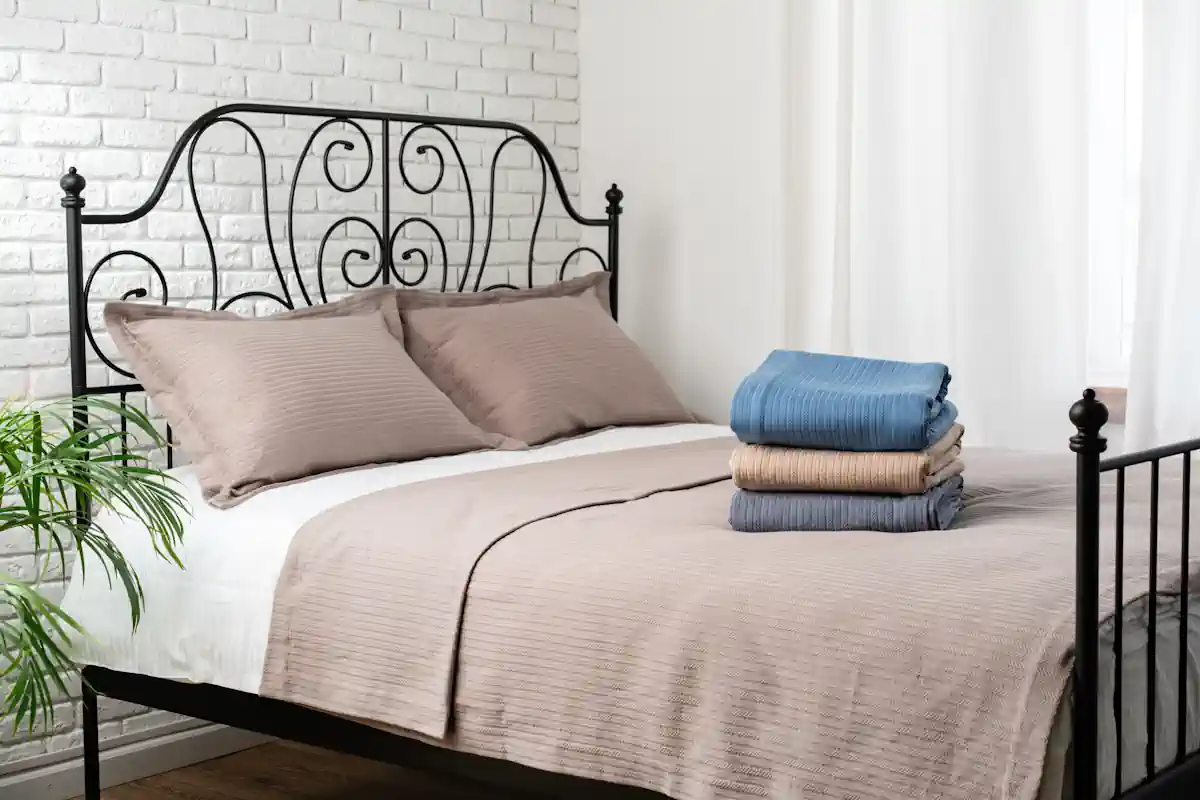 Un lit bien rangé avec une parure marron et d'autres choix de draps de différentes couleurs qui y sont posés