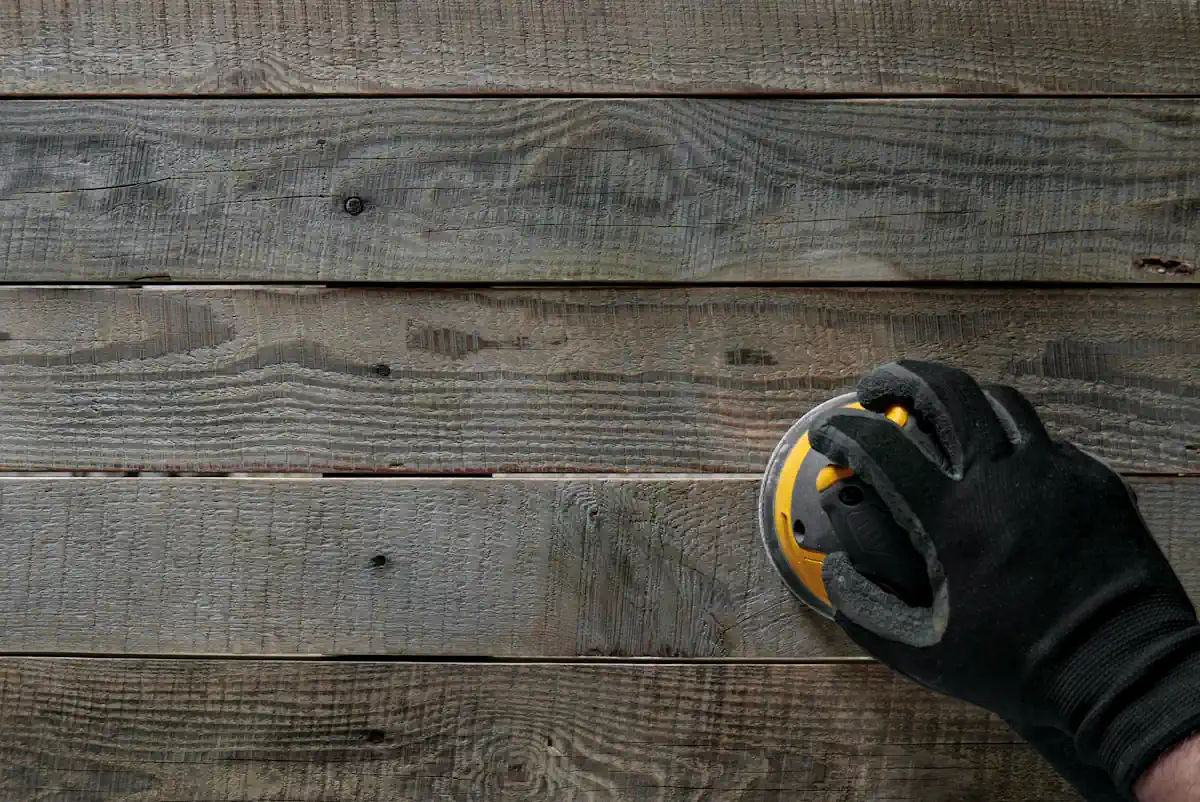 Une personne qui passe une ponceuse sur du bois