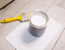 Un pot de sous-couche posé sur le sol à côté d'un pinceau