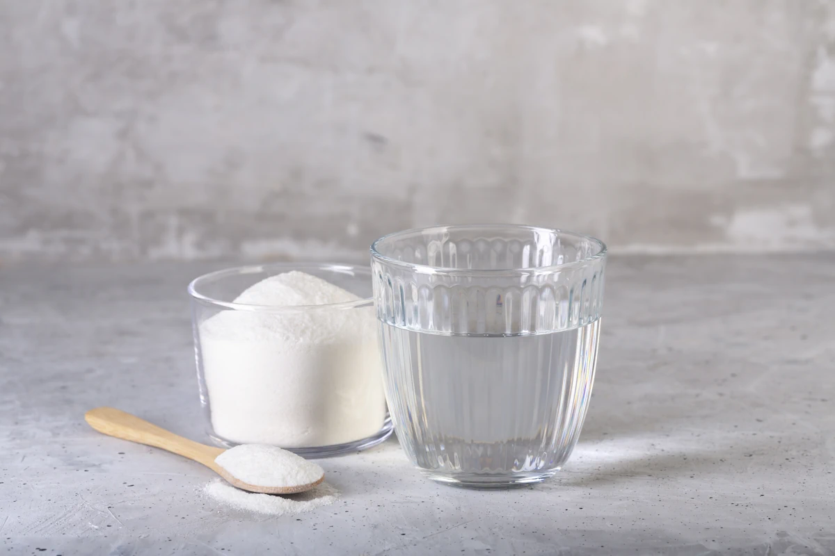 Vinaigre blanc et bicarbonate de soude à côté d'une cuillière en bois
