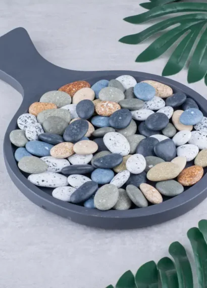 Des galets de différentes couleurs dans un contenant en pierre en forme de poele