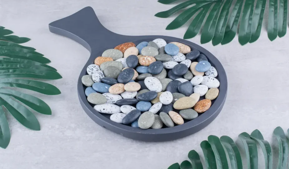 Des galets de différentes couleurs dans un contenant en pierre en forme de poele