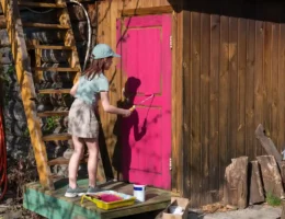 Une petite fille qui peint un abri de jardin en rose
