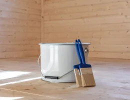 Un pot de peinture posé sur le sol avec deux pinceaux