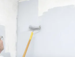 Une personne qui applique une sous-couche sur un mur