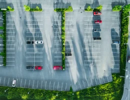 Un parking avec de la verdure et quelques voitures installées
