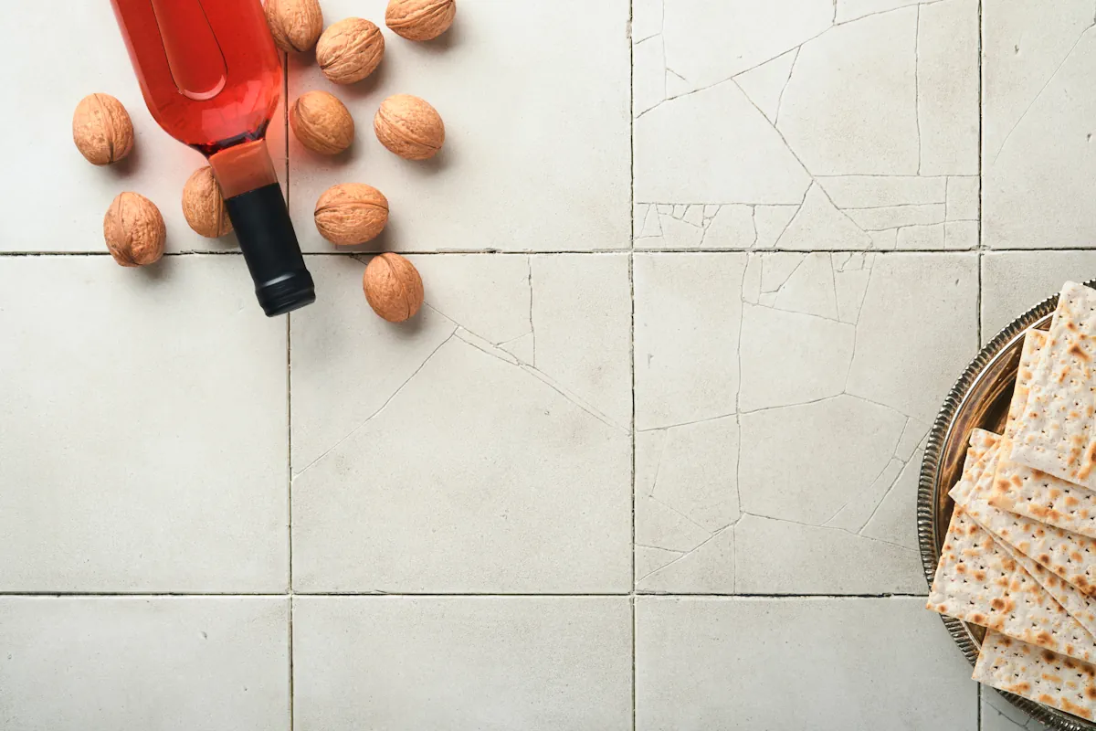 Un carrelage blanc avec des fissures où sont posés une bouteille de vins et quelques noix
