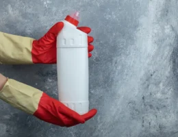 Une personne qui tient une bouteille de liquide déboucheur