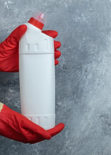 Une personne qui tient une bouteille de liquide déboucheur
