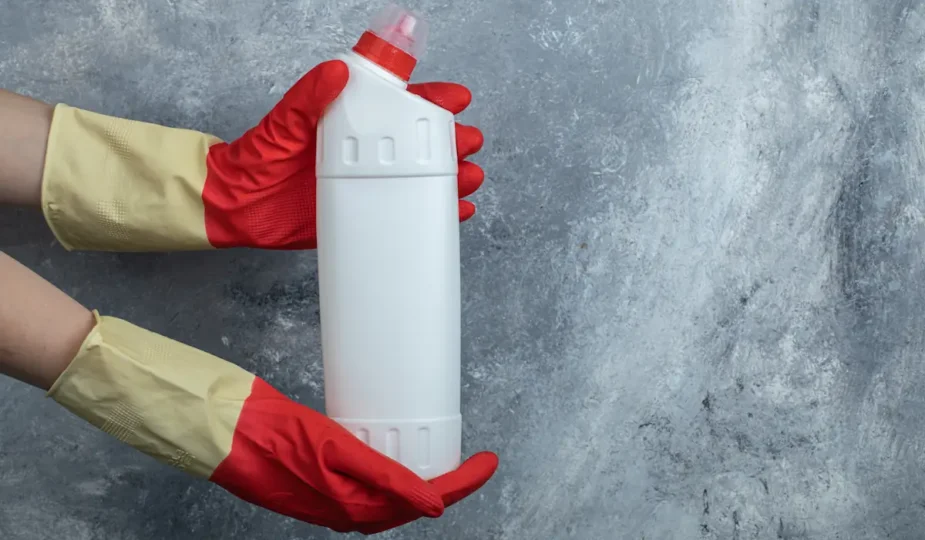 Une personne qui tient une bouteille de liquide déboucheur