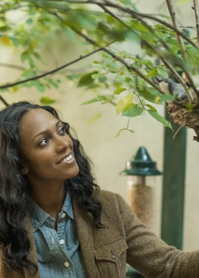 Une femme qui regarde des oiseaux dans un arbuste