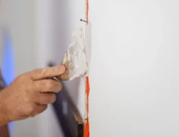 Une personne qui applique de l'enduit pour faire des bandes de placo