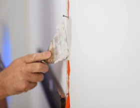Une personne qui applique de l'enduit pour faire des bandes de placo