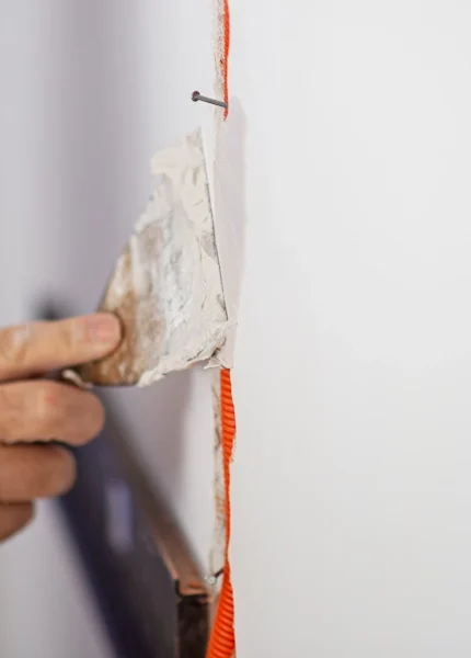 Une personne qui applique de l'enduit pour faire des bandes de placo