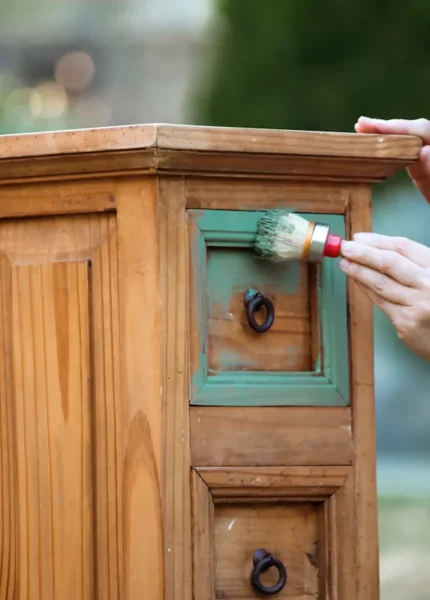Une personne qui peint un meuble en mérisier