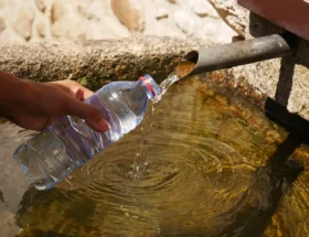 Une personne qui recueille l'eau d'un puit avec une bouteille d'eau
