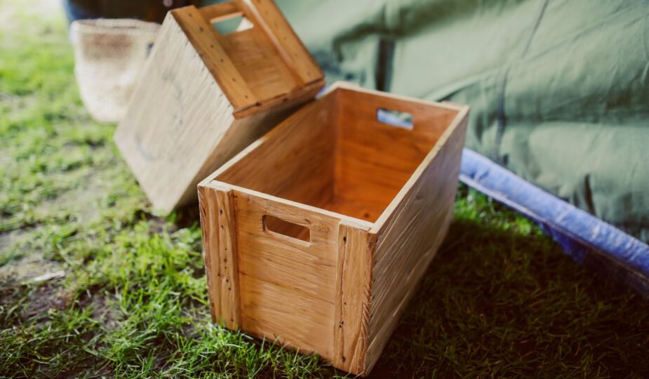 Rustic wooden crates placed on grass in a rural outdoor setting, perfect for garden decor.