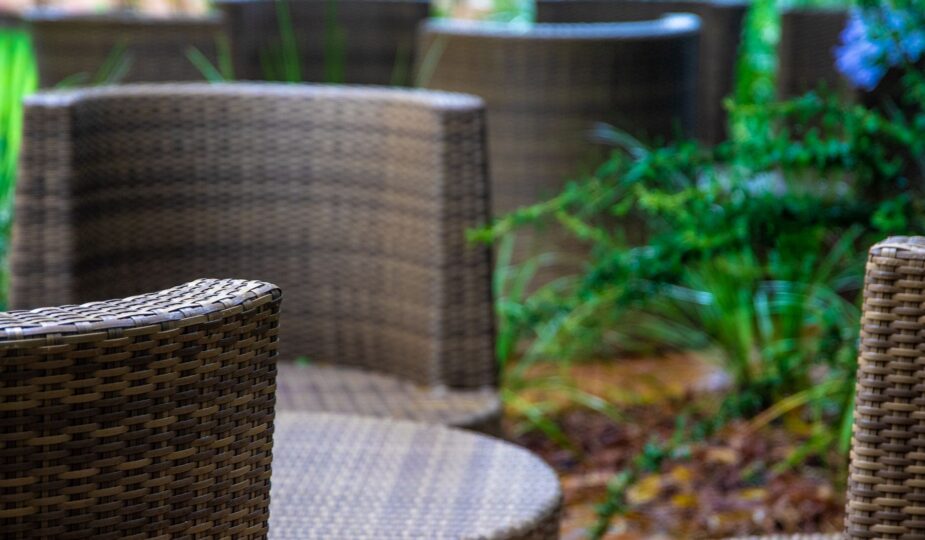 Close-up of wicker chairs in a tranquil garden setting, perfect for relaxation.