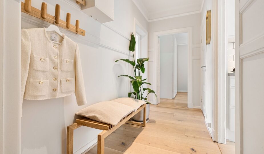 Bright minimalist hallway featuring wooden furniture and a stylish coat rack.