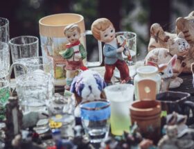 A collection of decorative figurines and glass items displayed on a table at a flea market.