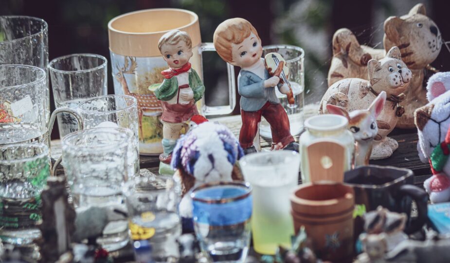 A collection of decorative figurines and glass items displayed on a table at a flea market.