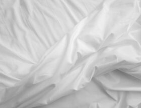 An elegant, close-up view of white satin sheets with a texture that evokes comfort and luxury.