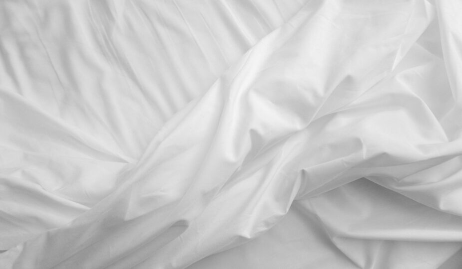 An elegant, close-up view of white satin sheets with a texture that evokes comfort and luxury.