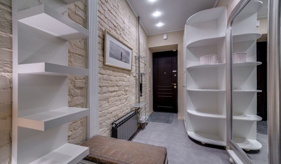 Contemporary entryway with sleek white shelving and neutral tones, featuring a comfortable bench.