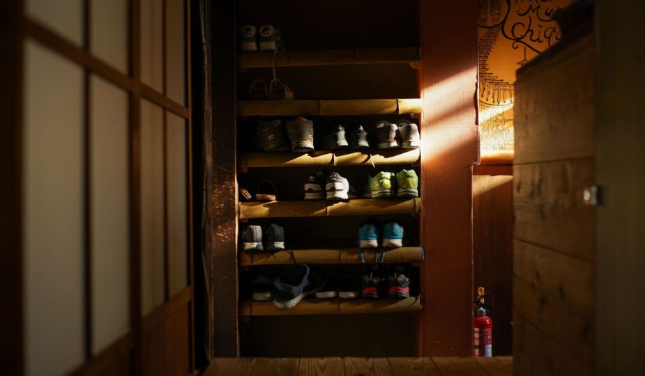 Warmly lit shoe rack featuring organized sneakers in a traditional Kyoto residence.