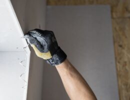 Close-up of a gloved hand applying plaster to a wall indoors in Falun, Sweden.