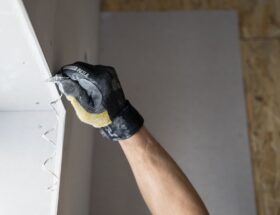 Close-up of a gloved hand applying plaster to a wall indoors in Falun, Sweden.