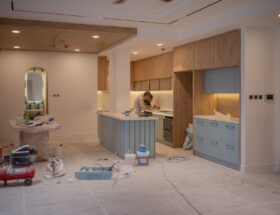 A modern kitchen undergoing renovation, featuring a worker, tools, and materials.
