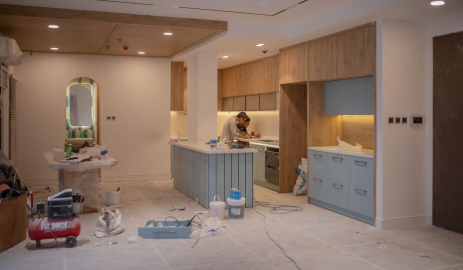 A modern kitchen undergoing renovation, featuring a worker, tools, and materials.