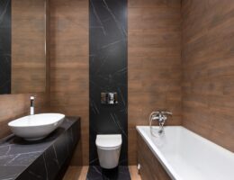 Sleek modern bathroom featuring wood paneling and marble accents, with a white basin and bathtub.