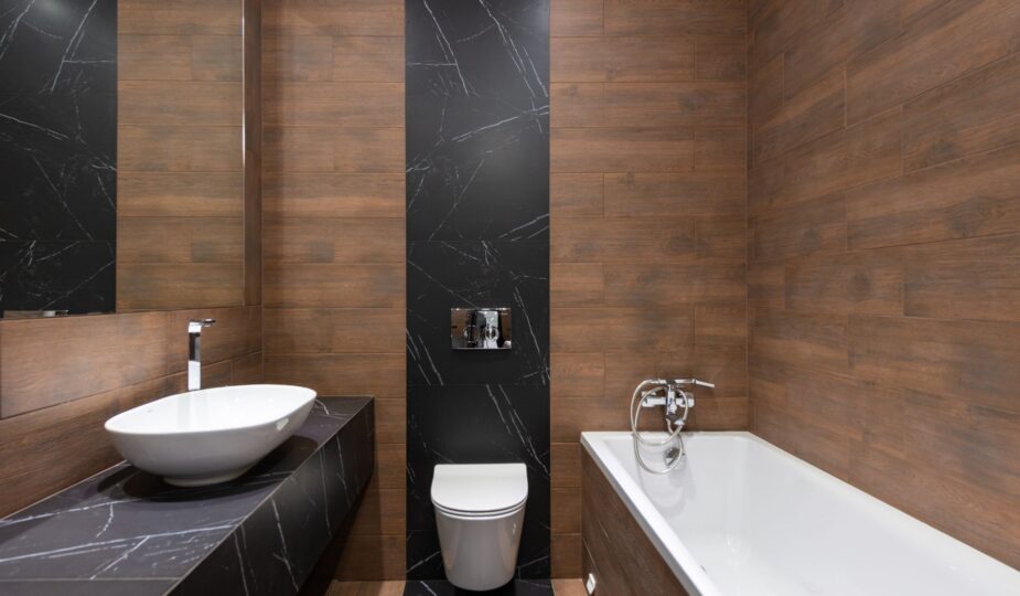 Sleek modern bathroom featuring wood paneling and marble accents, with a white basin and bathtub.