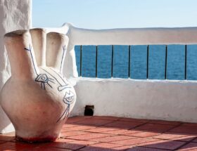 Abstract ceramic vase on a sunny terrace by the sea, blending art and nature.