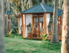 A serene wooden gazebo amidst palm trees in Phan Thiet, Vietnam, ideal for relaxation.
