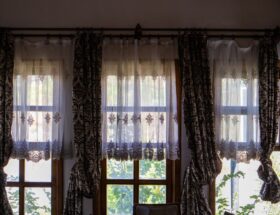 Sunlit room with elegant traditional curtains overlooking a garden view.